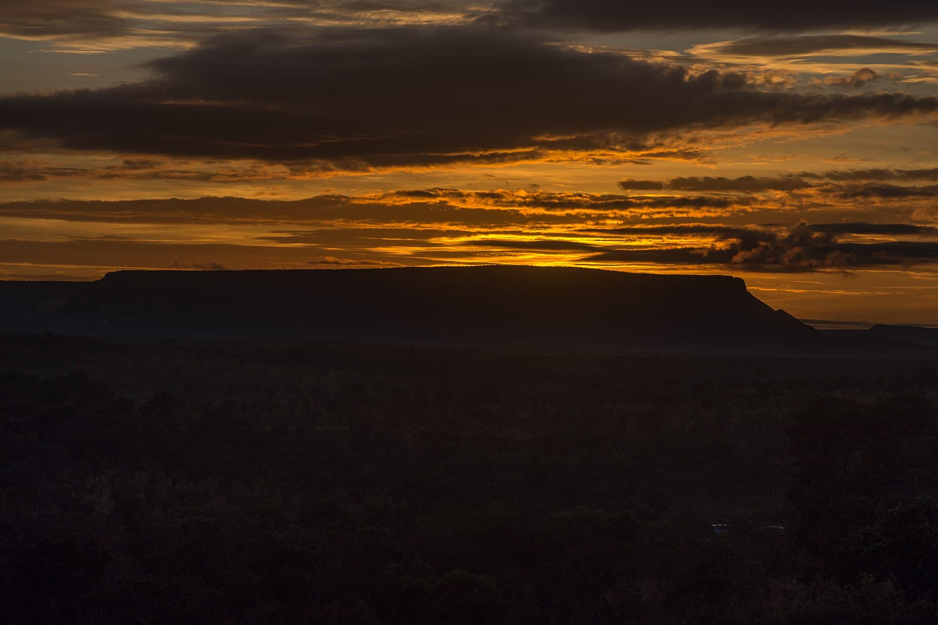 Pôr do sol alaranjado sobre a silhueta de uma serra no Cerrado do Tocantins